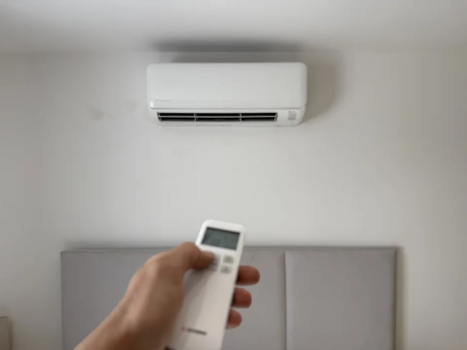 Wall-mounted air conditioning above a bed, operated with a handheld remote